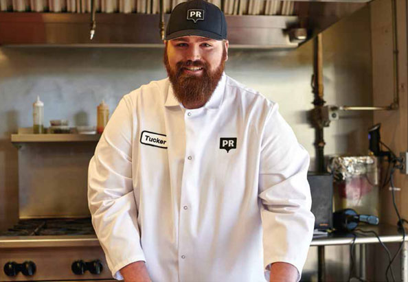 male in kitchen in uniform smiling